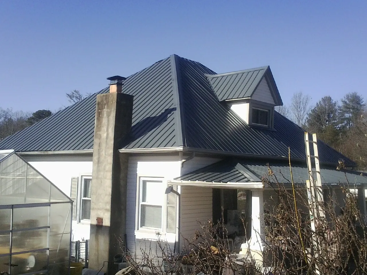 Dark blue standing seam metal roof on a white farmhouse with dormer — Slate & Tile Roof Repair by Roofing Brothers in Walthourville