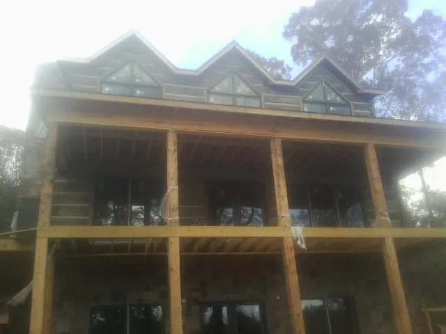 Dormers and porch framing on a large log home under construction — Roof Coating work by our crew in Walthourville