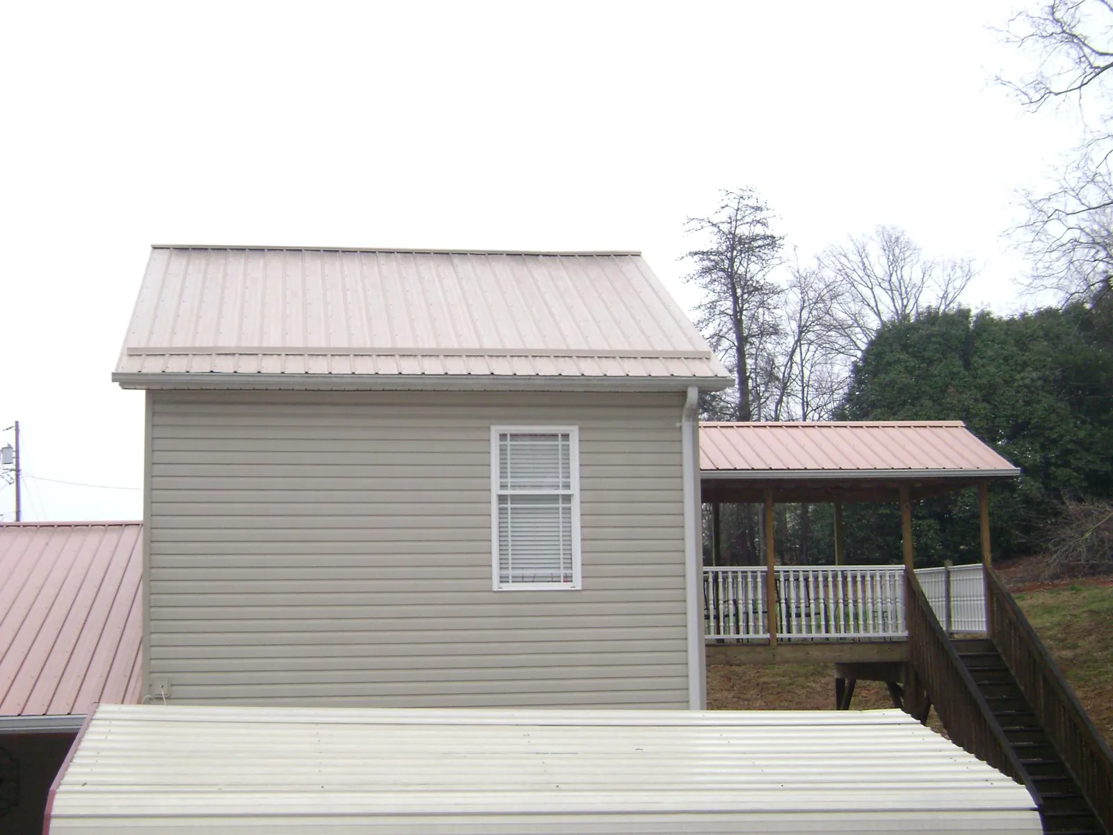 Tan metal roofs on a two story addition and attached porch, from a Roof Replacement job in Walthourville
