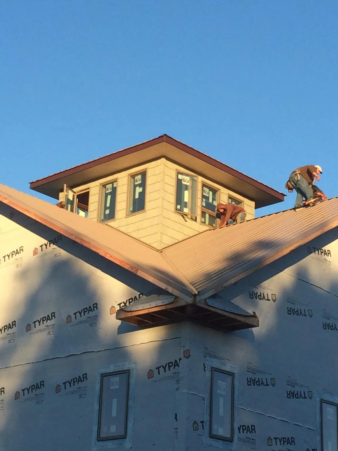 Roofers working around a rooftop cupola on a new metal roof at sunset — Roof Waterproofing in Walthourville by Roofing Brothers